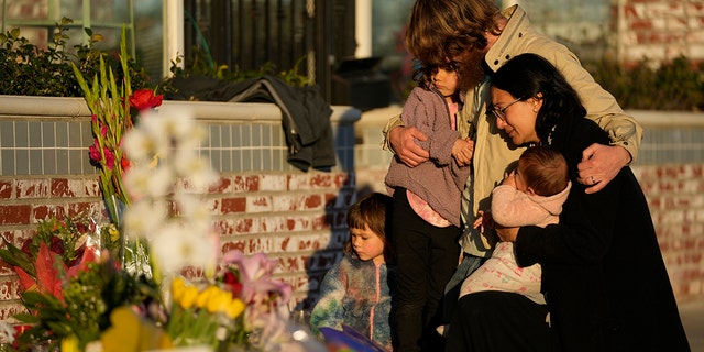 A family gathers at a memorial outside the Star Ballroom Dance Studio on Tuesday, Jan. 24, 2023, in Monterey Park, Calif. A gunman killed multiple people at the ballroom dance studio late Saturday amid Lunar New Year's celebrations in the predominantly Asian American community. 