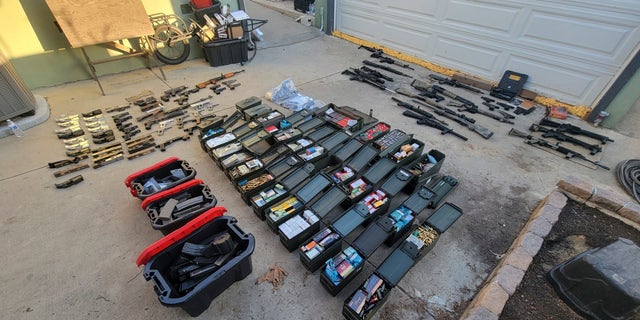 Nearly two dozen guns and thousands of rounds of ammunition are displayed following an arrest on Jan. 25, 2023, in Azusa, California. The guns were seized from the home of a man who had mental health problems.