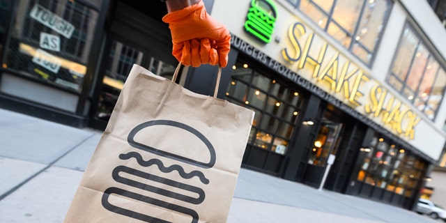 A person wearing a protective glove holds a bag outside Shake Shack during the coronavirus pandemic on April 20, 2020, in New York City.