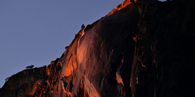 Water flowing off Horsetail Fall glows orange while backlit from the setting sun during the "Firefall" phenomenon in Yosemite National Park, California, on Feb. 15, 2023. 