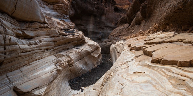 An asphalt trail leads through the smooth white polished marble walls in Mosaic Canyon. Death Valley National Park, California, U.S.