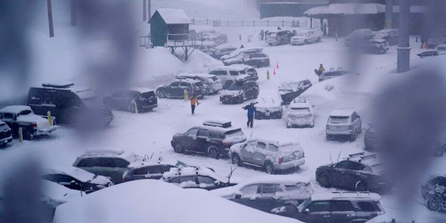 People through the parking area of the Alpine Base Area at Palisades Tahoe during a winter storm Friday, Feb. 24, 2023, in Alpine Meadows, California.