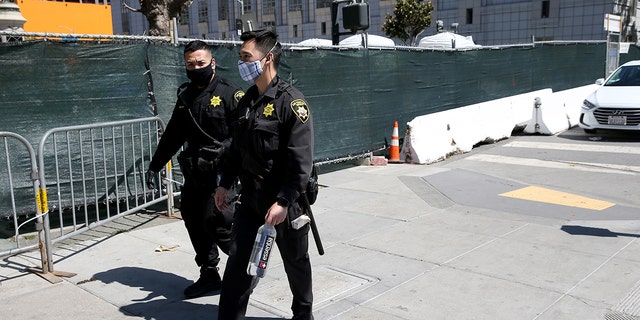 San Francisco County Sheriff's Office deputies pass by a sanctioned and fenced-in homeless encampment across from City Hall in San Francisco, on May 19, 2020.