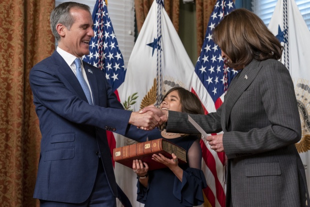 Eric Garcetti, left, next to his daughter Maya Garcetti holding a heavy and historic Hebrew Bible from the Library of Congress, is sworn in as Ambassador to India by Vice President Kamala Harris, Friday, March 24, 2023, in her ceremonial office in the Eisenhower Executive Office Building on the White House complex in Washington. (AP Photo/Jacquelyn Martin)