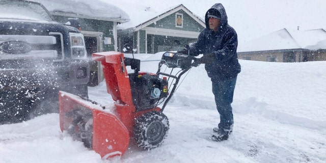 Tony Delafield works to clear his driveway of snow in Bellemont, Ariz., on Wednesday, March 1, 2023. In Arizona, snow began falling Wednesday morning as the storm moved eastward and was poised to dump as much as 2 feet (60 centimeters) of snow in northern Arizona by Thursday morning. 