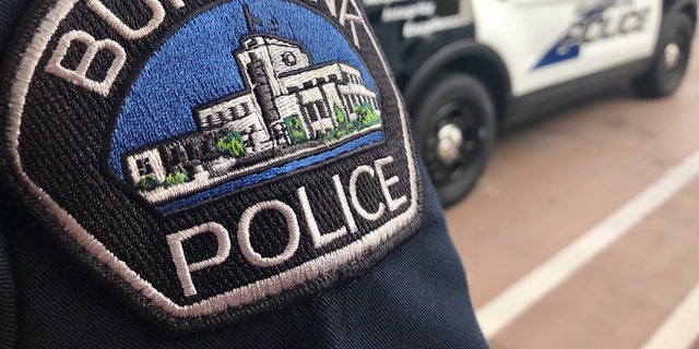 A Burbank, California police officer stands behind a Burbank police cruiser.