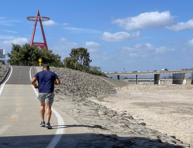 A runner heads north on the Santa Ana River Trail near Angel Stadium in Anaheim, CA, on Monday, May 9, 2022.During the late spring or summer, the Orange County Water District typically cleans out the recharge basins, removing sediments left behind by water from the previous season's rains. (Photo by Jeff Gritchen, Orange County Register/SCNG)