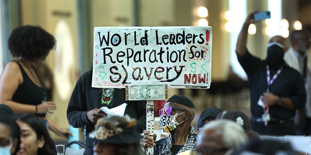 LA resident holds up sign demanding reparations for slavery