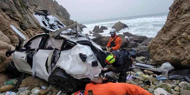 emergency personnel respond to a vehicle over the side of Highway 1 on Jan. 1, 2023