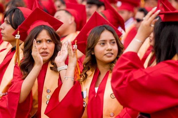 Kamila Gallego, left, and Melanie Cruz Peralta, center, help direct fellow graduate Belky Arroyo, right, adjust her graduation cap during the Loara High School graduation ceremonies in Handel Stadium at Western High School in Anaheim on Thursday, May 25, 2023. (Photo by Leonard Ortiz, Orange County Register/SCNG)