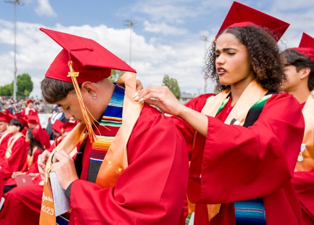 Michael Serrano, left, gets help with his sash from Angelina Shaw as they lineup to receive their diploma during the Loara High School graduation ceremonies in Handel Stadium at Western High School in Anaheim on Thursday, May 25, 2023. (Photo by Leonard Ortiz, Orange County Register/SCNG)