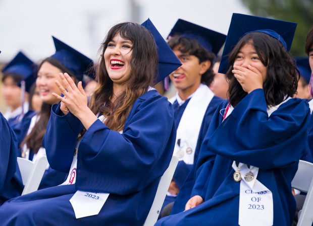 Alexandra Pereira, left, and Kaile Ouchi, right, burst into  laughter as graduates watch a Class of 2022 memories slide show during the Oxford Academy graduation ceremonies in Handel Stadium at Western High School in Anaheim on Tuesday, May 23, 2023. (Photo by Leonard Ortiz, Orange County Register/SCNG)