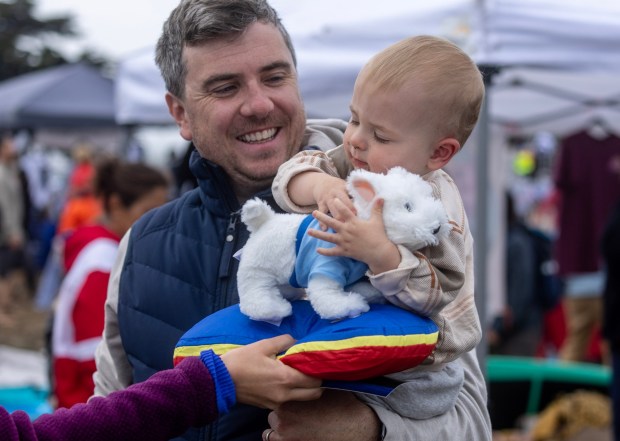 Eric Kovalkoski's 14-month-old son, Lukas, falls for a stuffed animal bought at the World Dog Surfing Championships, Saturday, Aug. 5, 2023, at Linda Mar Beach in Pacifica, Calif. (Karl Mondon/Bay Area News Group)