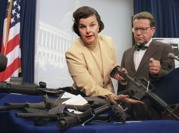 FILE - Sen. Dianne Feinstein, D-Calif., left, accompanied by Sen. Paul Simon, D-Ill., holds an AR-15 assault-style rifle with a collapsible stock during a Capitol Hill news conference Friday March 22, 1996, after the House voted to repeal the two-year-old assault-style firearms ban. Democratic Sen. Dianne Feinstein of California has died. Three people familiar with the situation confirmed her death to The Associated Press on Friday, Sept. 29, 2023. She was 90. (AP Photo/John Duricka, File)