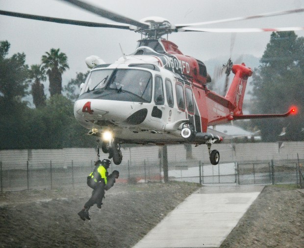 An LA firefighter holds onto the man he just plucked from the Pacoima Wash Monday, Feb. 5, 2024, after the manjumped into the rain-swollen flood-control channel in the Sylmar area in an attempt to rescue his dog. Los Angeles firefighters were able to pluck him out of the water about 3 miles downstream. The dog managed to get out of the fast-moving water on its own. (Photo by Mike Meadows/Special to the Los Angeles Daily News)