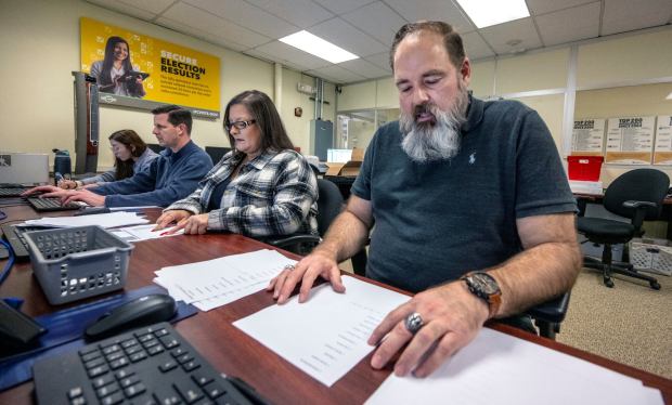 James Wight, right, reads names and numbers to Danyette Sayles, both Orange County Registrar of Voters staff members, as they check the accuracy of scanned test ballots from Verity Scan devices that are used in voting centers throughout Orange County, on Friday, Feb. 9, 2024, in Santa Ana. The marked test ballots and scanning are part of a state-mandated logic and accuracy testing of the machines and processes of the OC Registrar of Voters, which is done for Californiaxe2x80x99s upcoming March 5th primary. (Photo by Mark Rightmire, Orange County Register/SCNG)