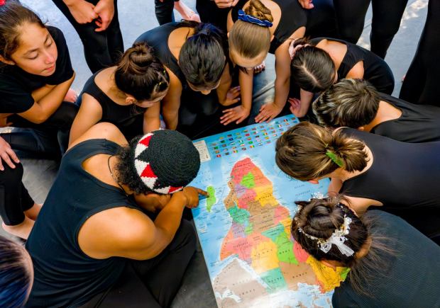 Students from The Wooden Floor join performer Sameola xe2x80x9cSammy Andriamalalaharijaona, left, of Madagascar as he points out his home country on a map in Santa Ana on Friday, Feb. 2, 2024. The Wooden Floor partnered with Chapman Universityxe2x80x99s Musco Center for the Arts to provide six master classes to all The Wooden Floor student, free of charge. ..Small Island Big Song is an artistic collective of singers, musicians, and dancers from island nations in the Indian and Pacific Oceans that perform their traditional dances and songs. Small Island Big Song will be performing at the Musco Center for the Arts on Feb. 3. (Photo by Leonard Ortiz, Orange County Register/SCNG)