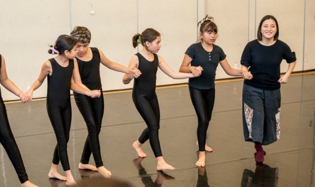 Small Island Big Song performer Yun xe2x80x9cYumaxe2x80x9d Chien, right, of Taiwan guides students from The Wooden Floor in a dance during a master class in Santa Ana on Friday, Feb. 2, 2024. The Wooden Floor partnered with Chapman Universityxe2x80x99s Musco Center for the Arts to provide six master classes to all The Wooden Floor student, free of charge. ..Small Island Big Song is an artistic collective of singers, musicians, and dancers from island nations in the Indian and Pacific Oceans that perform their traditional dances and songs. Small Island Big Song will be performing at the Musco Center for the Arts on Feb. 3. (Photo by Leonard Ortiz, Orange County Register/SCNG)