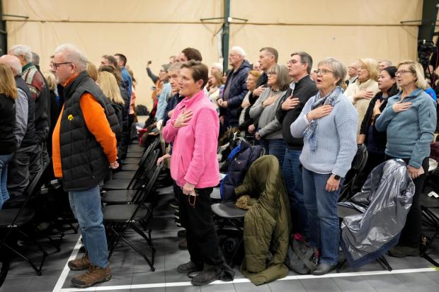 FILE - People stand and recite the Pledge of Allegiance at a caucus site in Clive, Iowa, Jan. 15, 2024. Super Tuesday is feeling anything but for many Americans, with the leading presidential contenders already appearing set. A primary season that engages only a fraction of the electorate to choose the presidential candidates is a reminder of how the U.S. election system excludes many voters and differs starkly from that of most other democracies around the world. (AP Photo/Andrew Harnik, File)