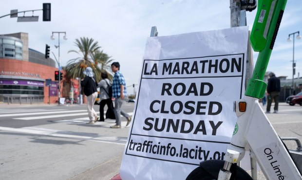 On Wednesday, March 13, 2024, people walk in Little Tokyo past a sign announcing the road closure, one of many, for Sunday, March 17, 2024 for the running of the 39th annual Los Angeles Marathon. (Photo by Dean Musgrove, Los Angeles Daily News/SCNG)