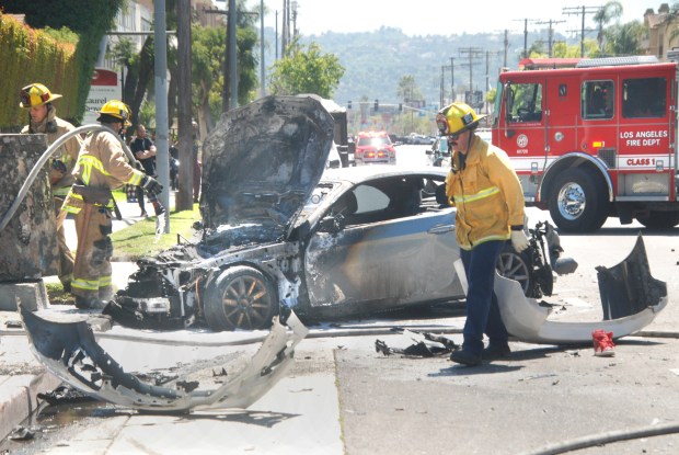 Los Angeles firefighters extinguish a car fire Wednesday, April 10, 2024, on Laurel Canyon Boulevard south of Oxnard Street in Valley Glen after an LAPD pursuit ended with a crash that injured a woman in another vehicle as well as the suspect in this BMW sedan. The injured male suspect was pulled from the burning vehicle by LAPD officers and hospitalized. (Photo by Mike Meadows/Contributing Photographer)