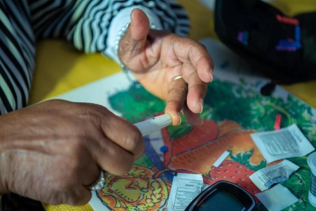 Barbara Williams pricks her finger using a home blood glucose monitoring kit.